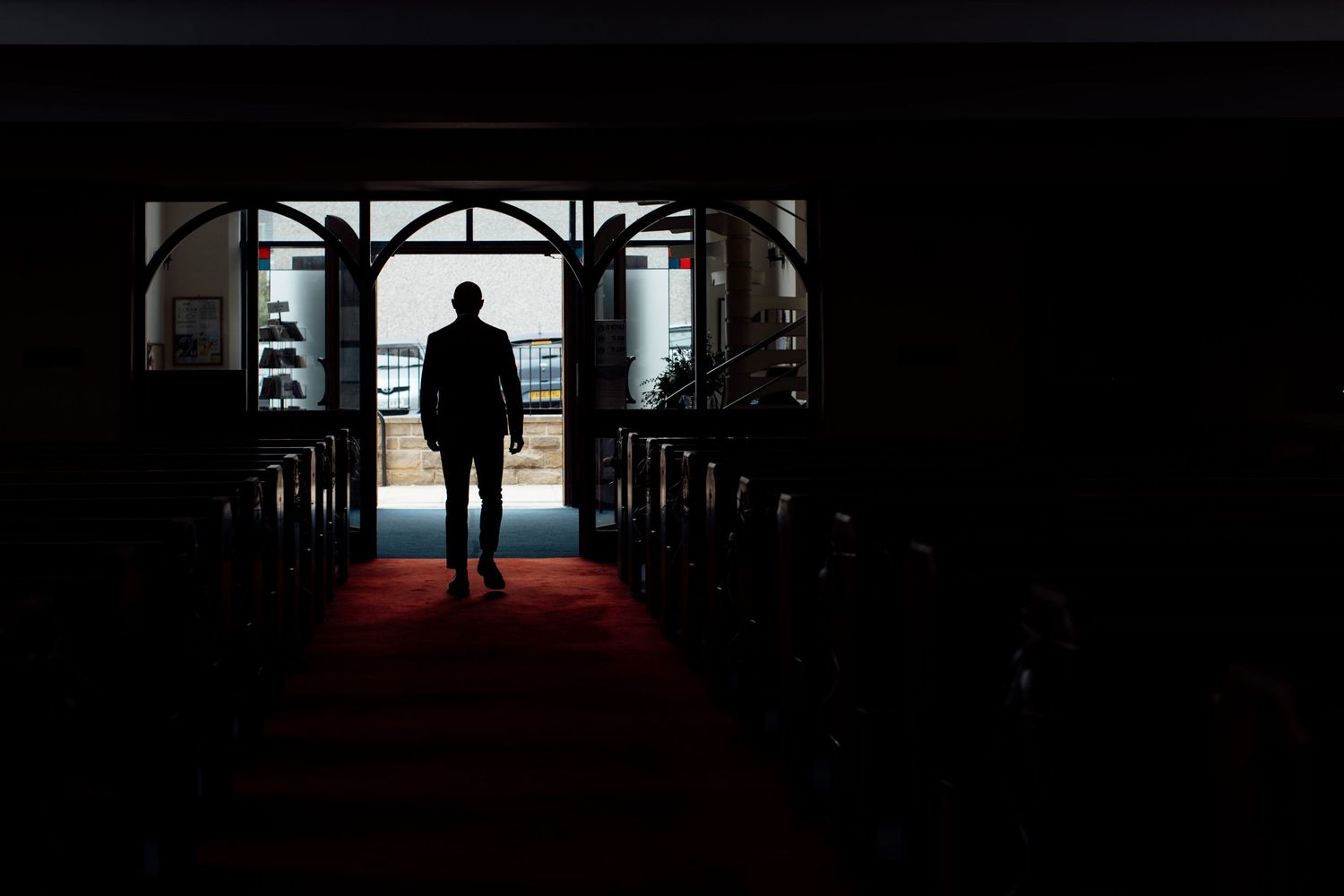Silhouettes of people walking through a dark hallway with dramatic lighting.