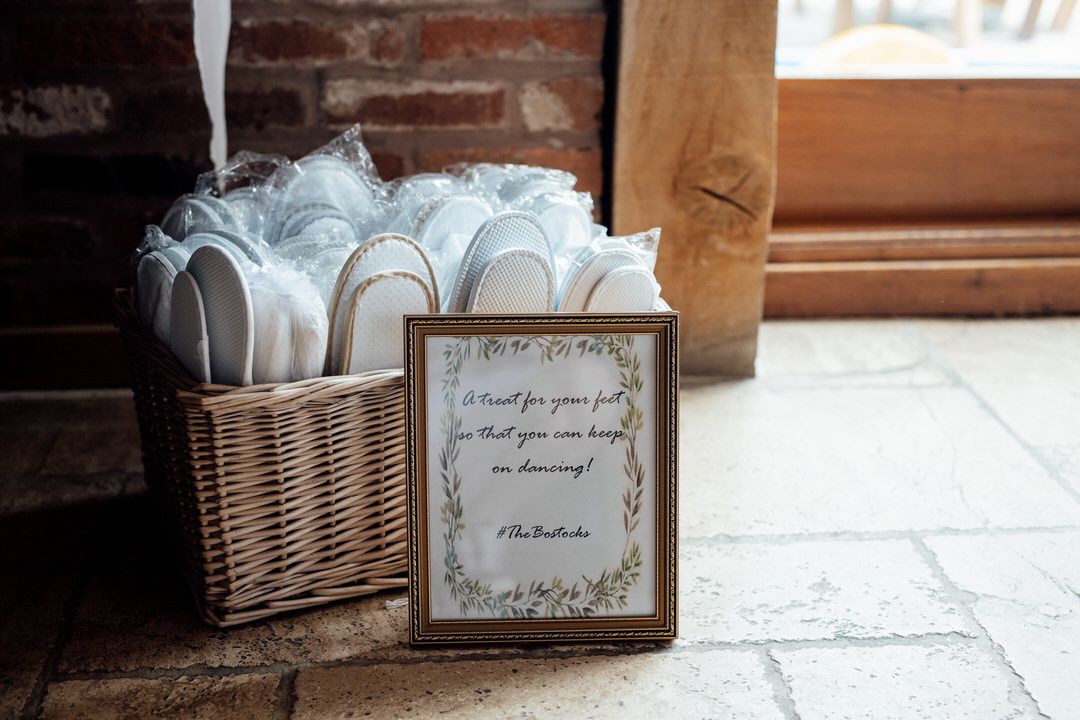 Wedding favor basket with framed sign and white paper fans against brick wall.