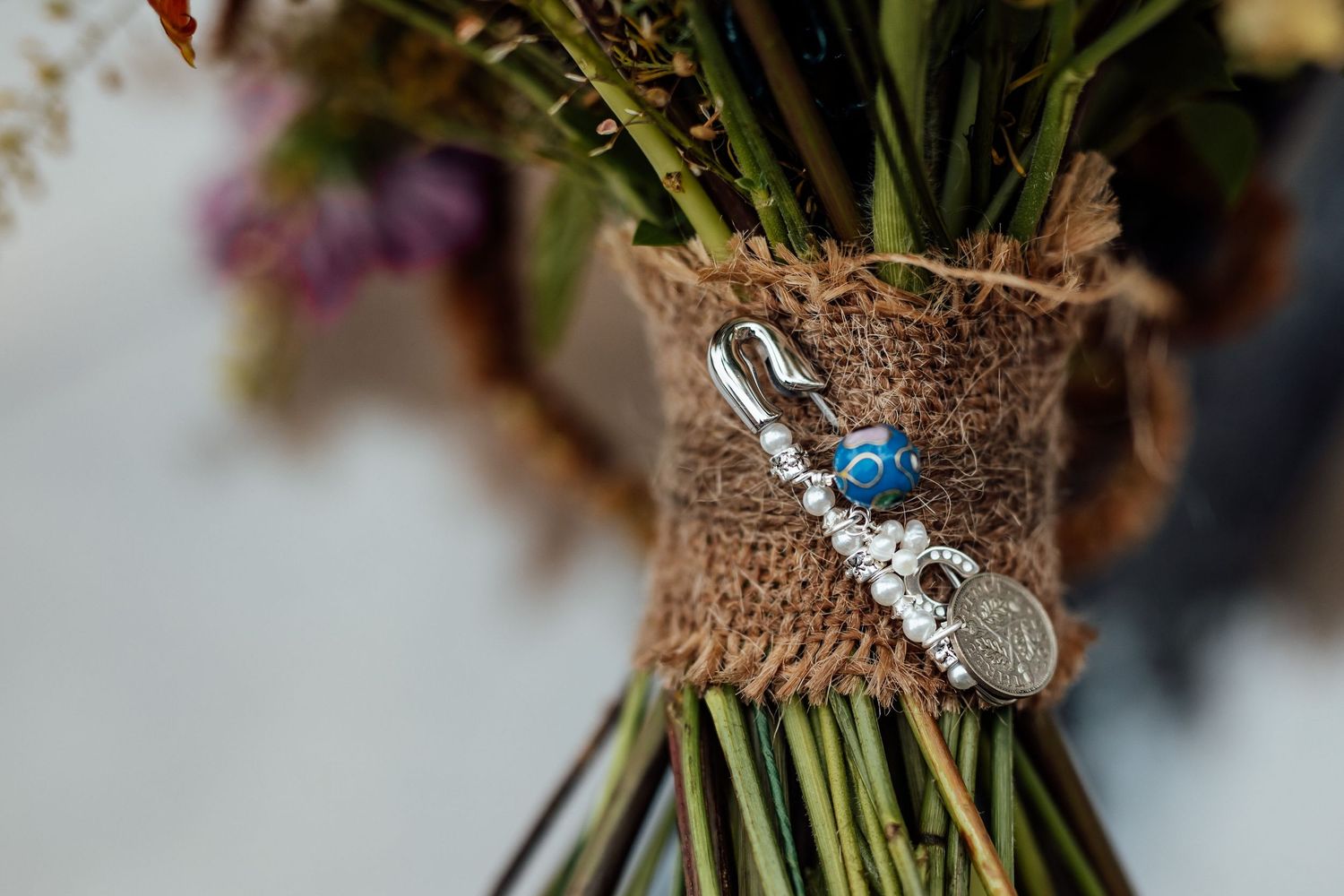 Wedding bouquet detail showing delicate charms and ribbons wrapped around stems.