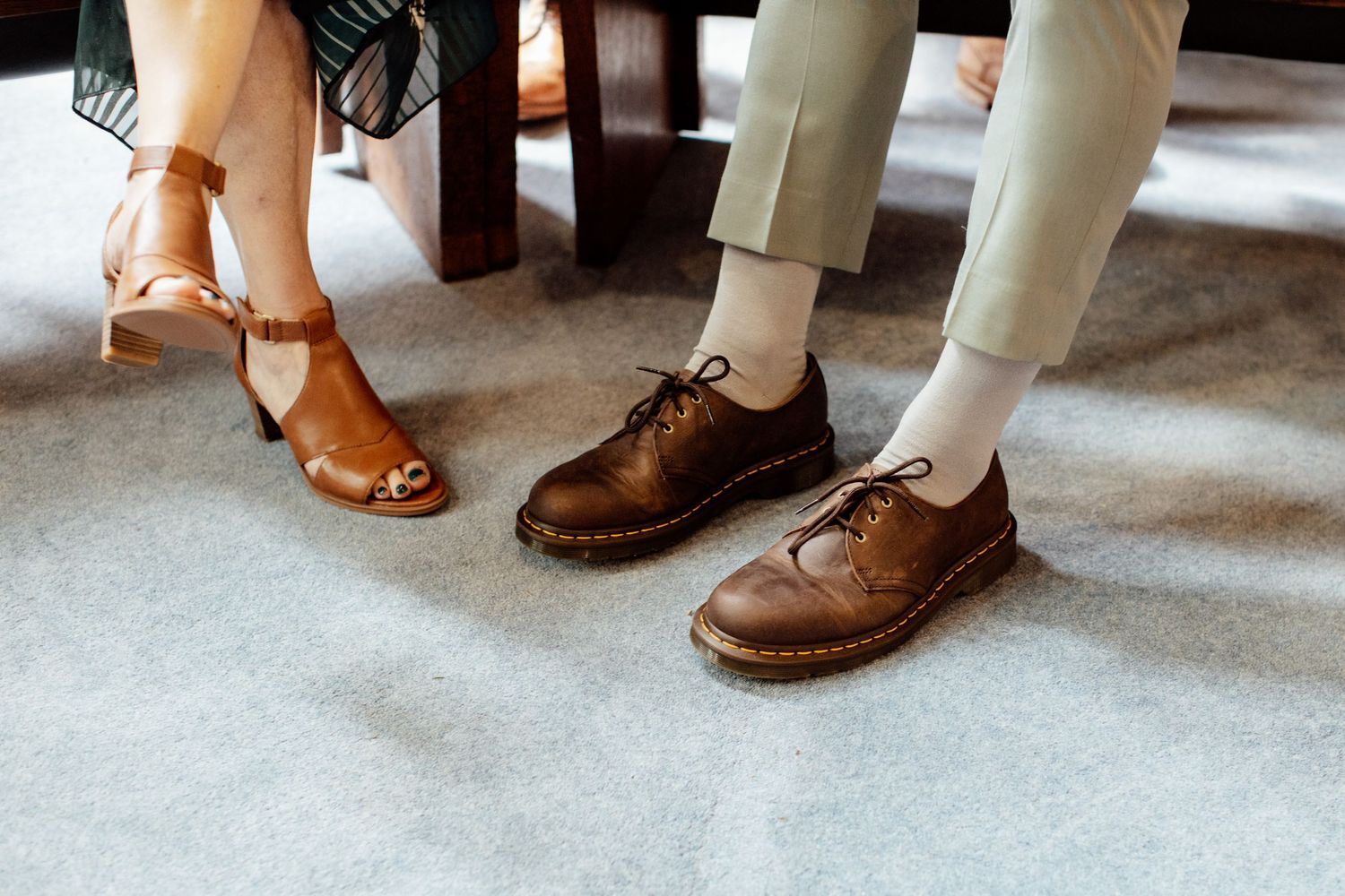 Various wedding shoes and footwear lined up on a light colored floor.