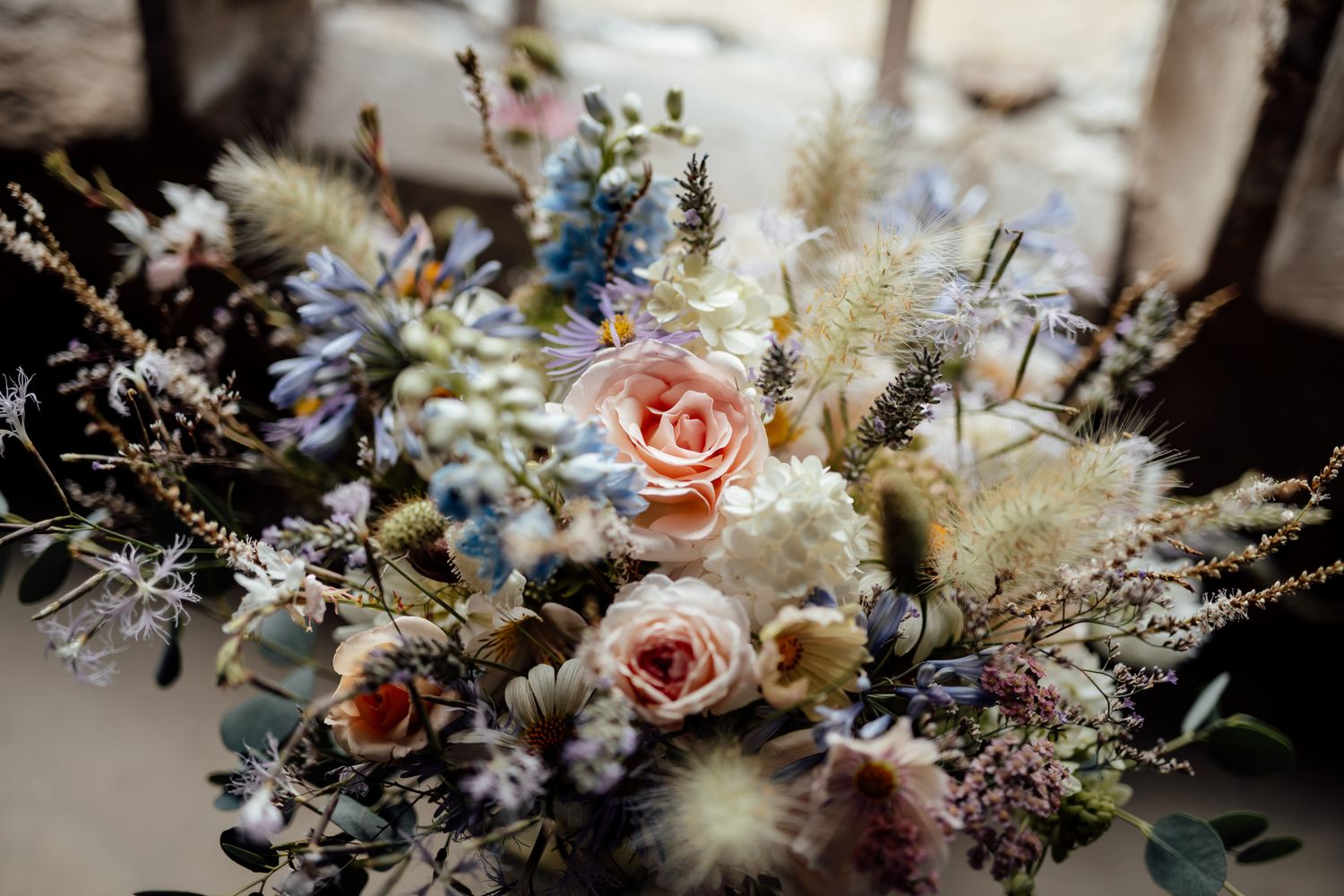 Elegant floral arrangements with pink roses and dried flowers on display at a wedding.