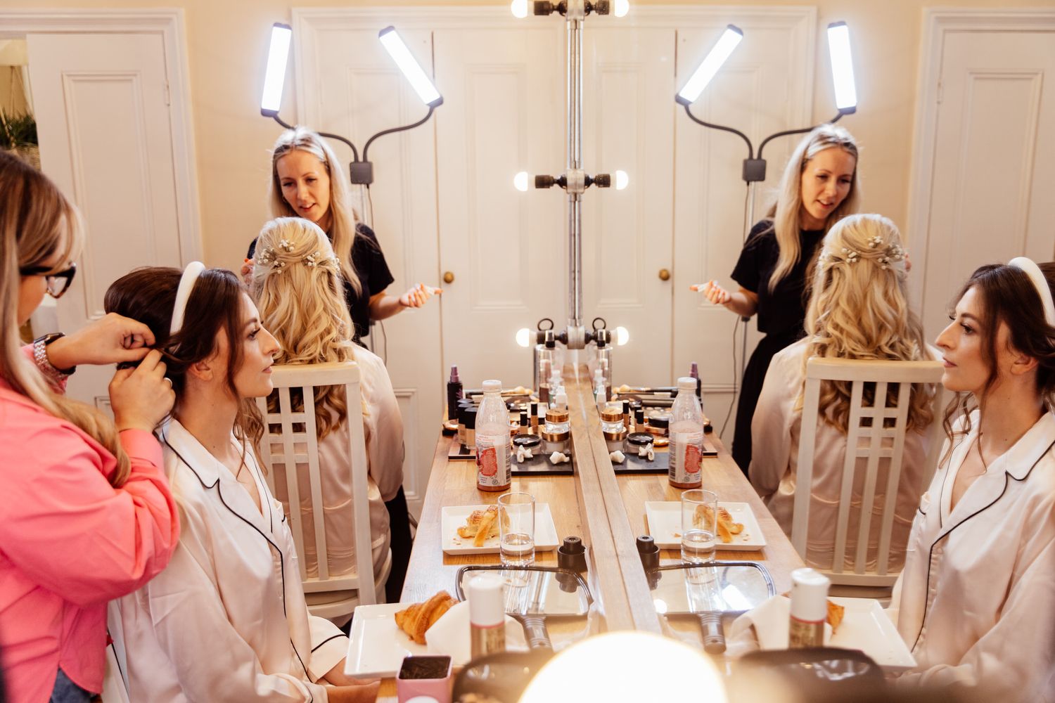 Wedding preparation scene with makeup stations and mirrors in a bright indoor setting.