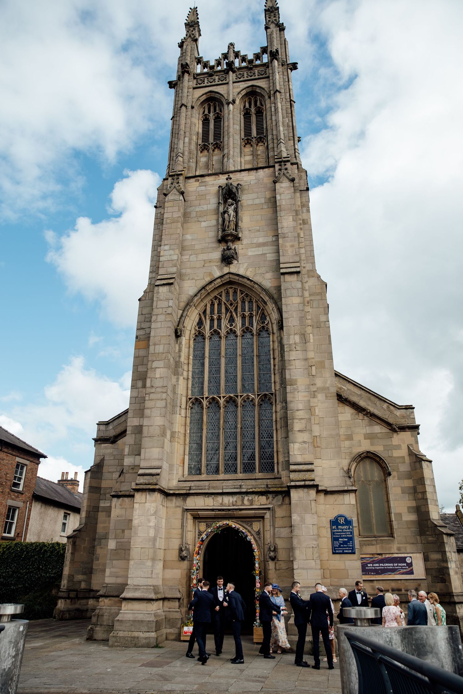 Gothic stone church exterior with tall spires and arched windows on a cloudy day.