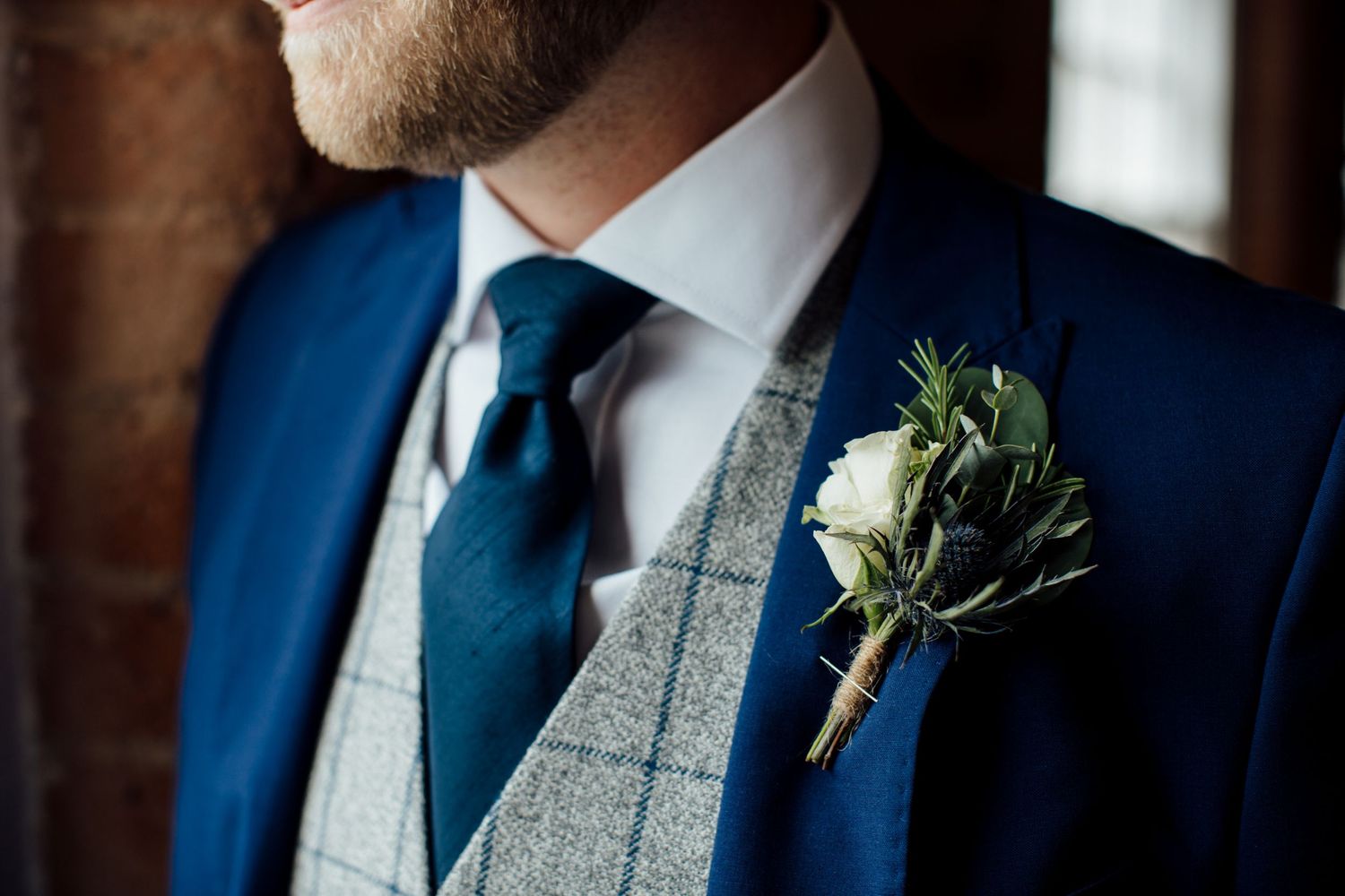 Formal attire details showing navy suits with gray vests and white boutonnieres.