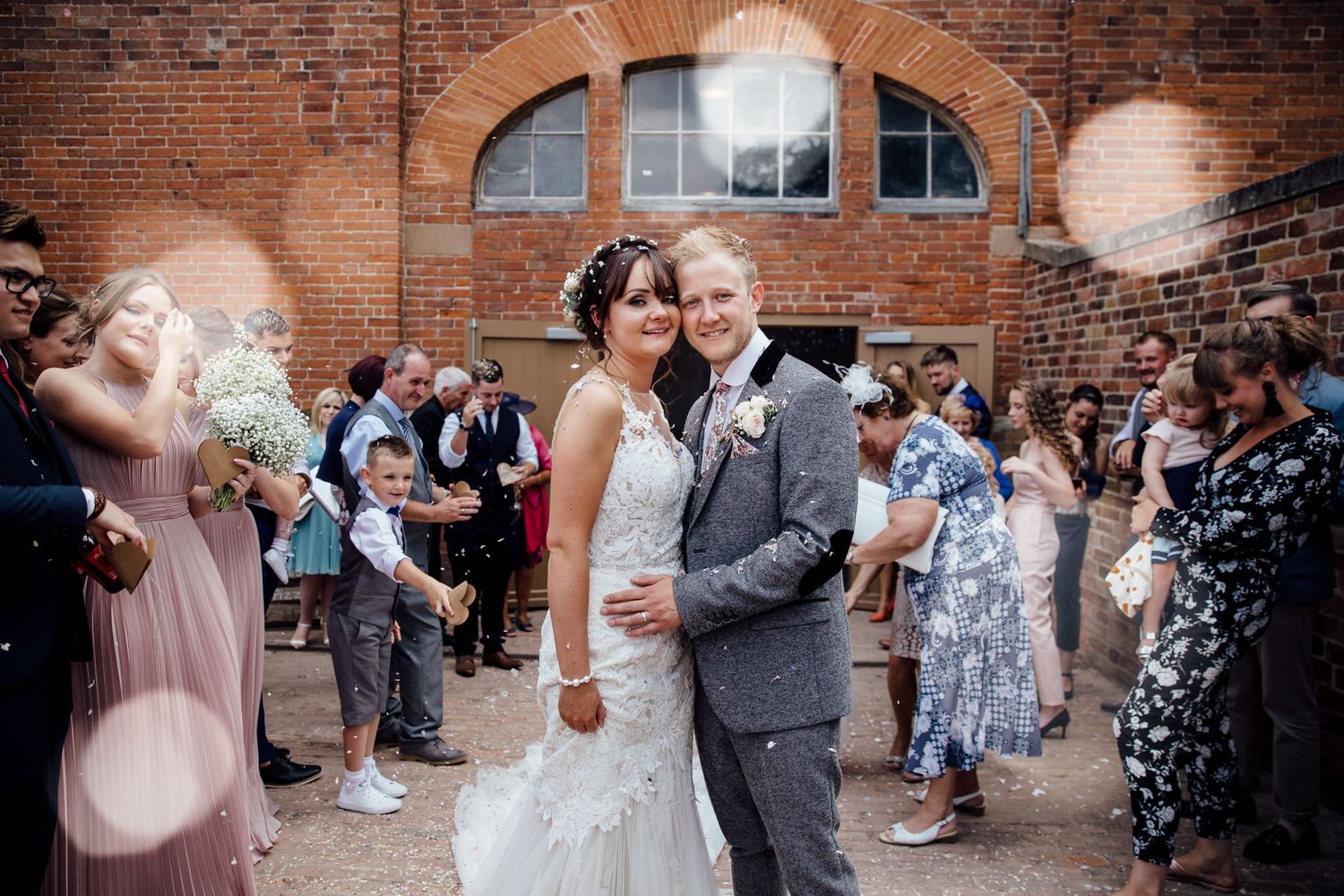 Wedding celebration outside a historic brick building with an arched entrance.