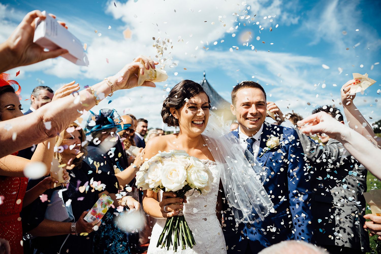 Celebratory moment with confetti tossing against bright blue sky.