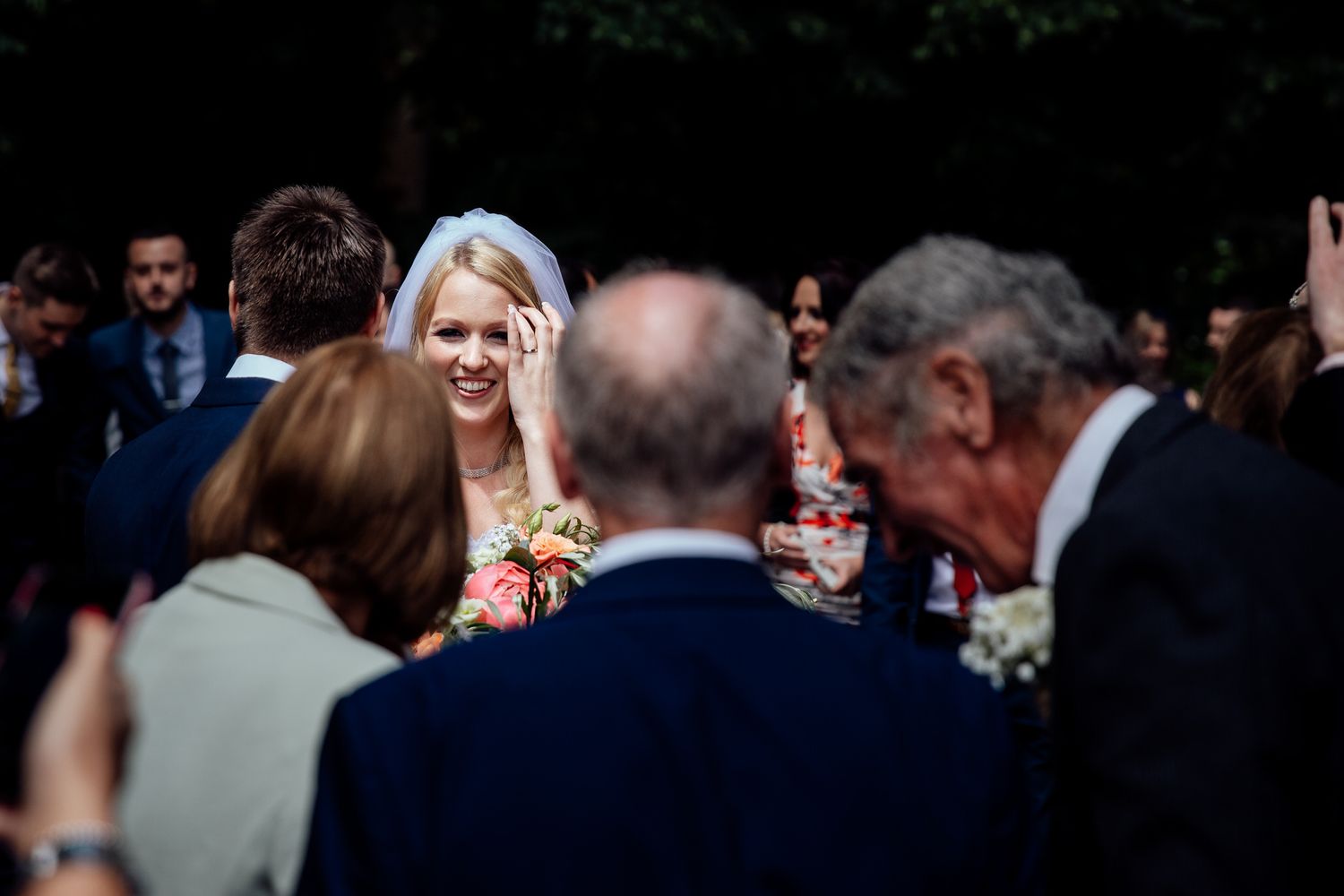 Wedding party guests celebrate during an outdoor reception in formal attire.