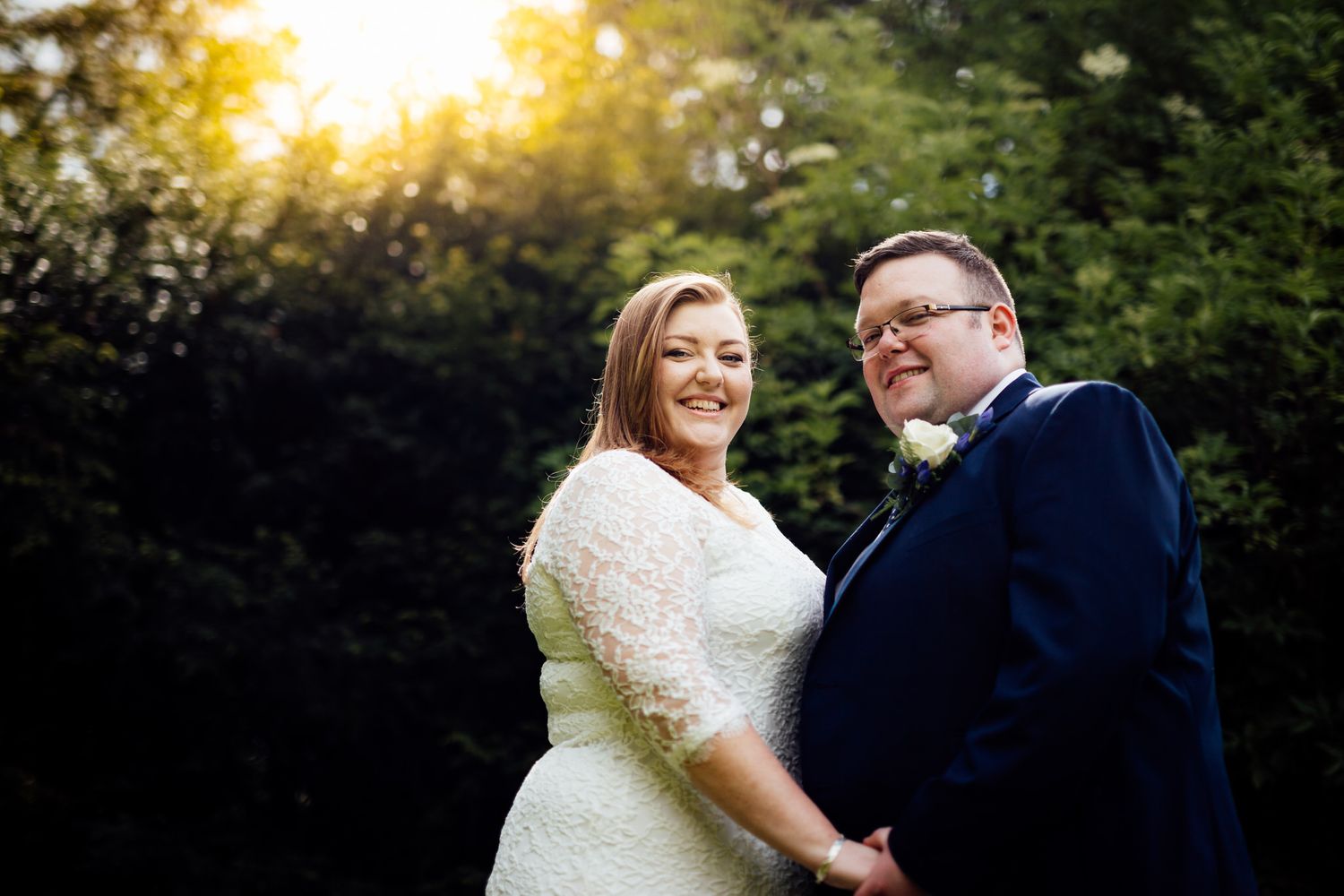 Couple shares an intimate moment at sunset in a garden setting.