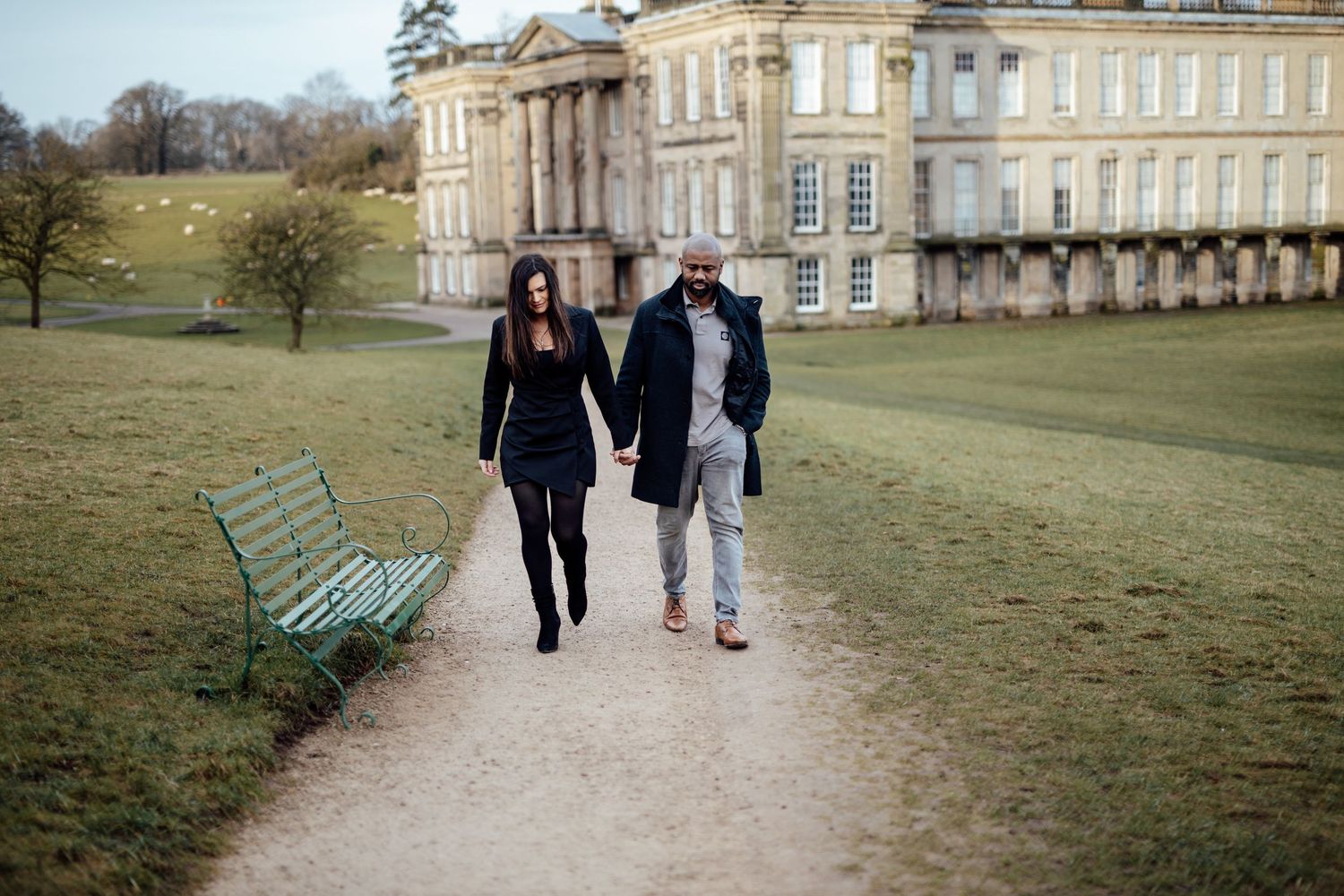 Couple walking together on the grounds of a grand historic mansion estate on a winter day.