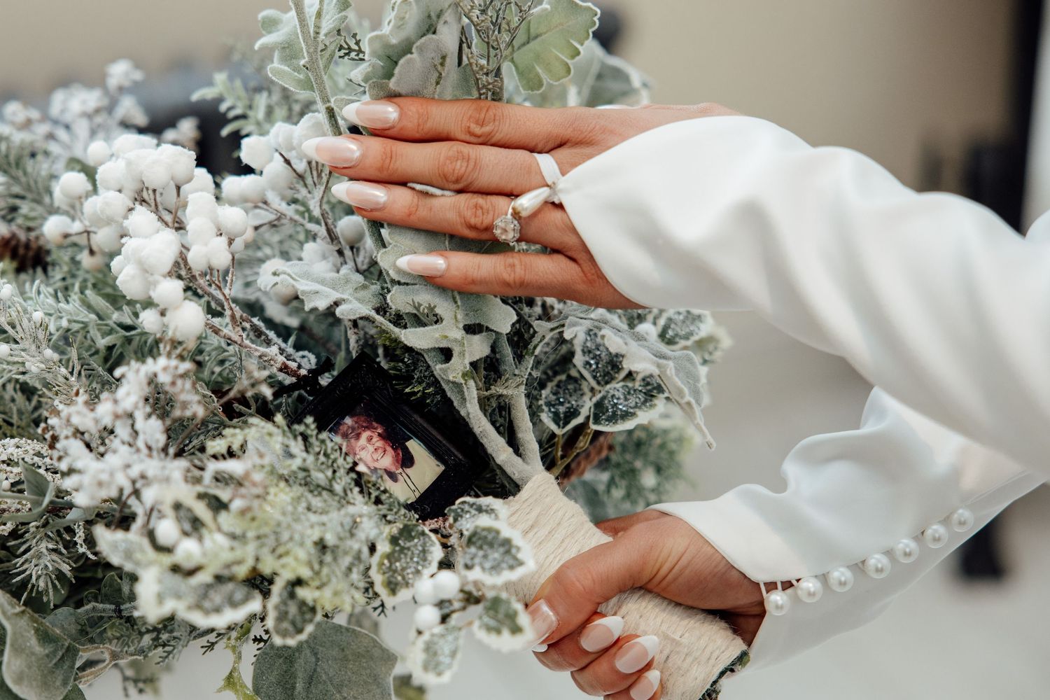 Close-up shots of hands delicately arranging white and silver winter wedding floral arrangements.
