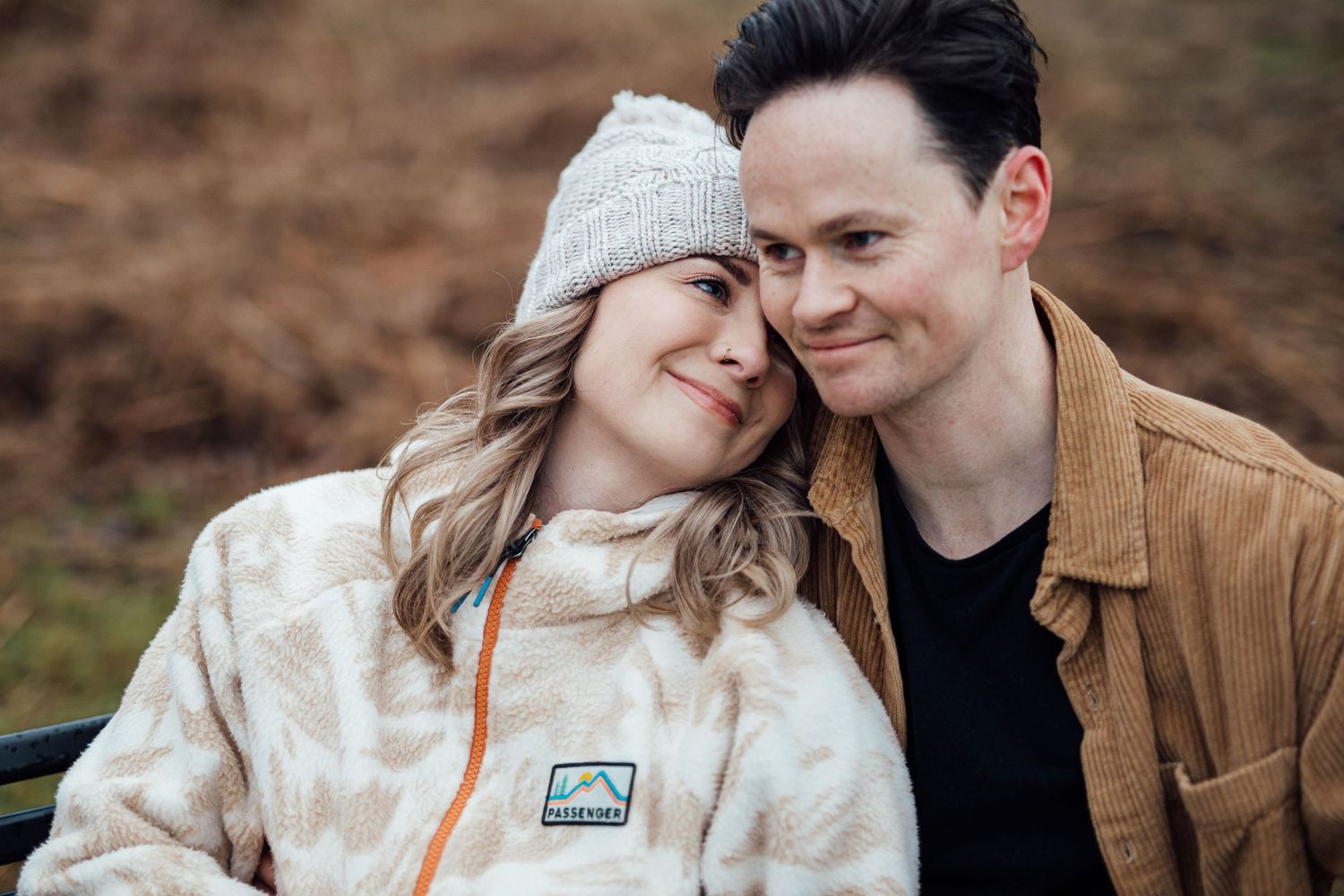 Affectionate couple in casual winter wear sharing tender moments during an outdoor photoshoot.