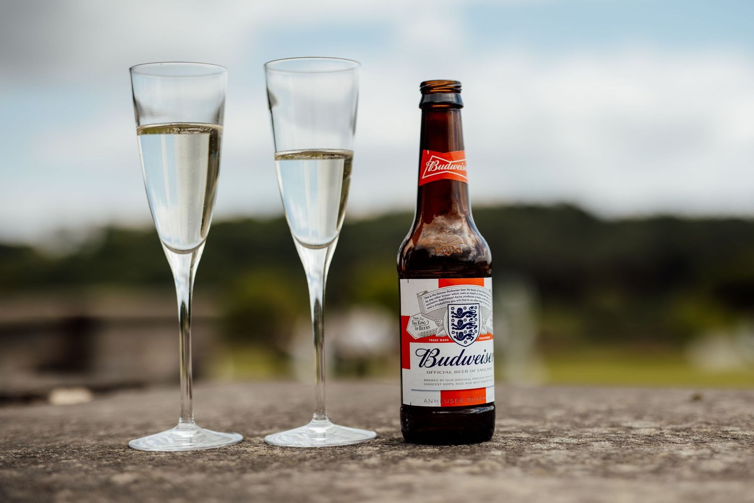 Wedding reception drinks with champagne flutes and beer bottles on stone surface.