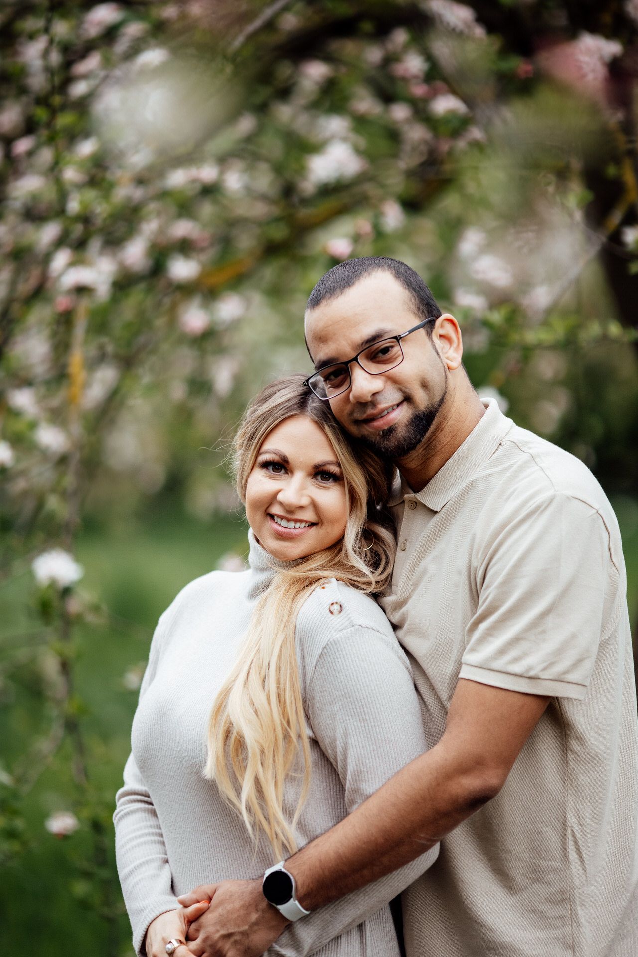A couple embraces among blooming spring flowers during an outdoor photo session.