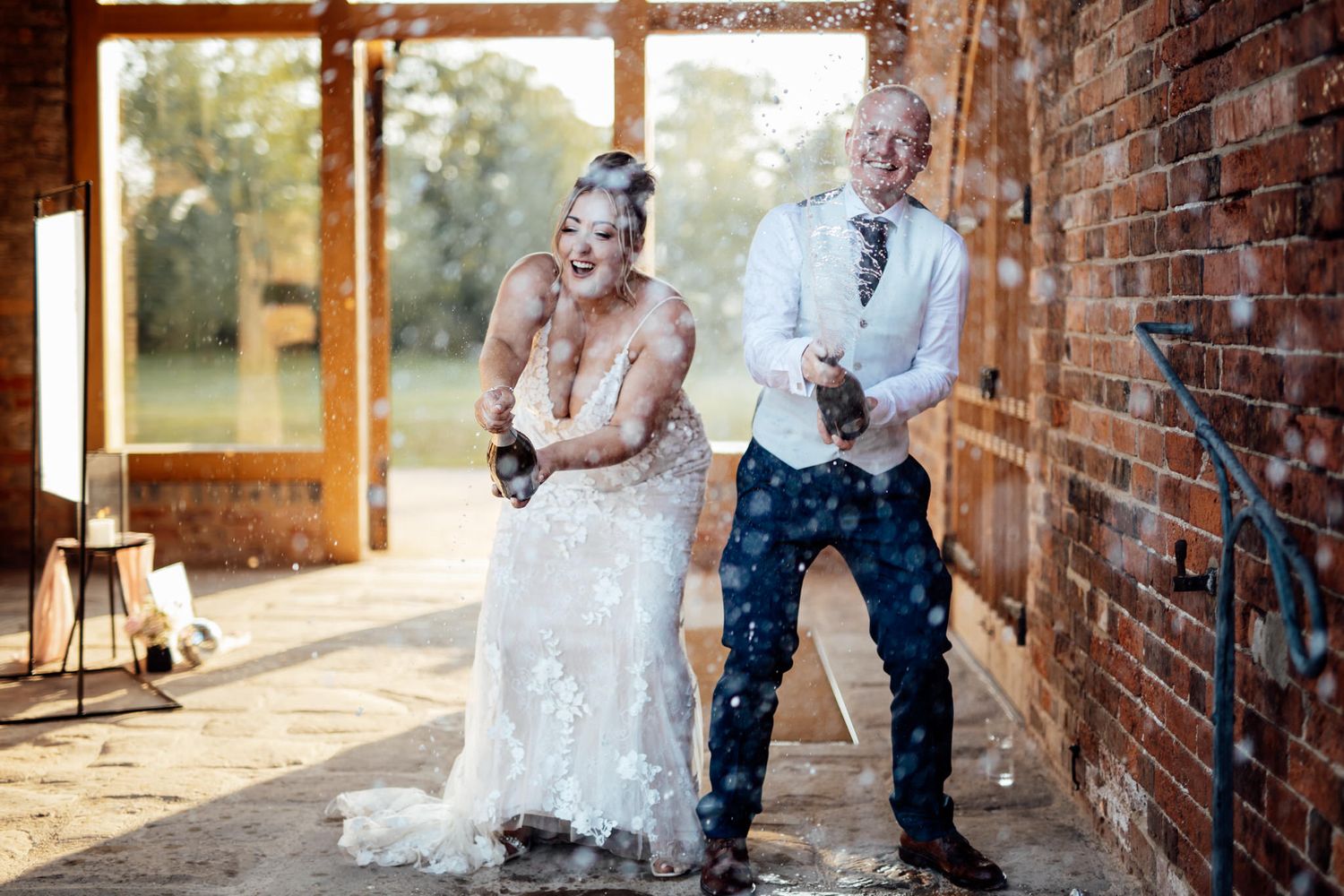 Sunlit wedding portraits taken against rustic brick walls and wooden windows.