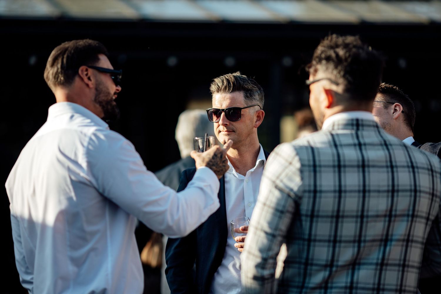 Wedding guests in casual attire mingle and socialize outdoors.