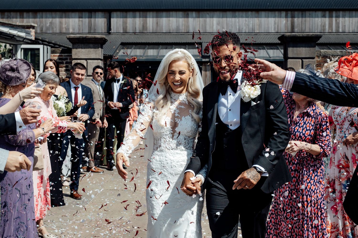 Joyful wedding celebration with confetti being thrown outdoors.