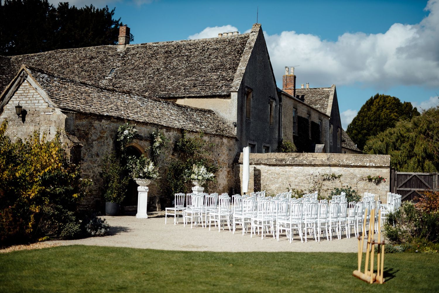 Stone country house wedding venue with white chairs set up for outdoor ceremony on the lawn.