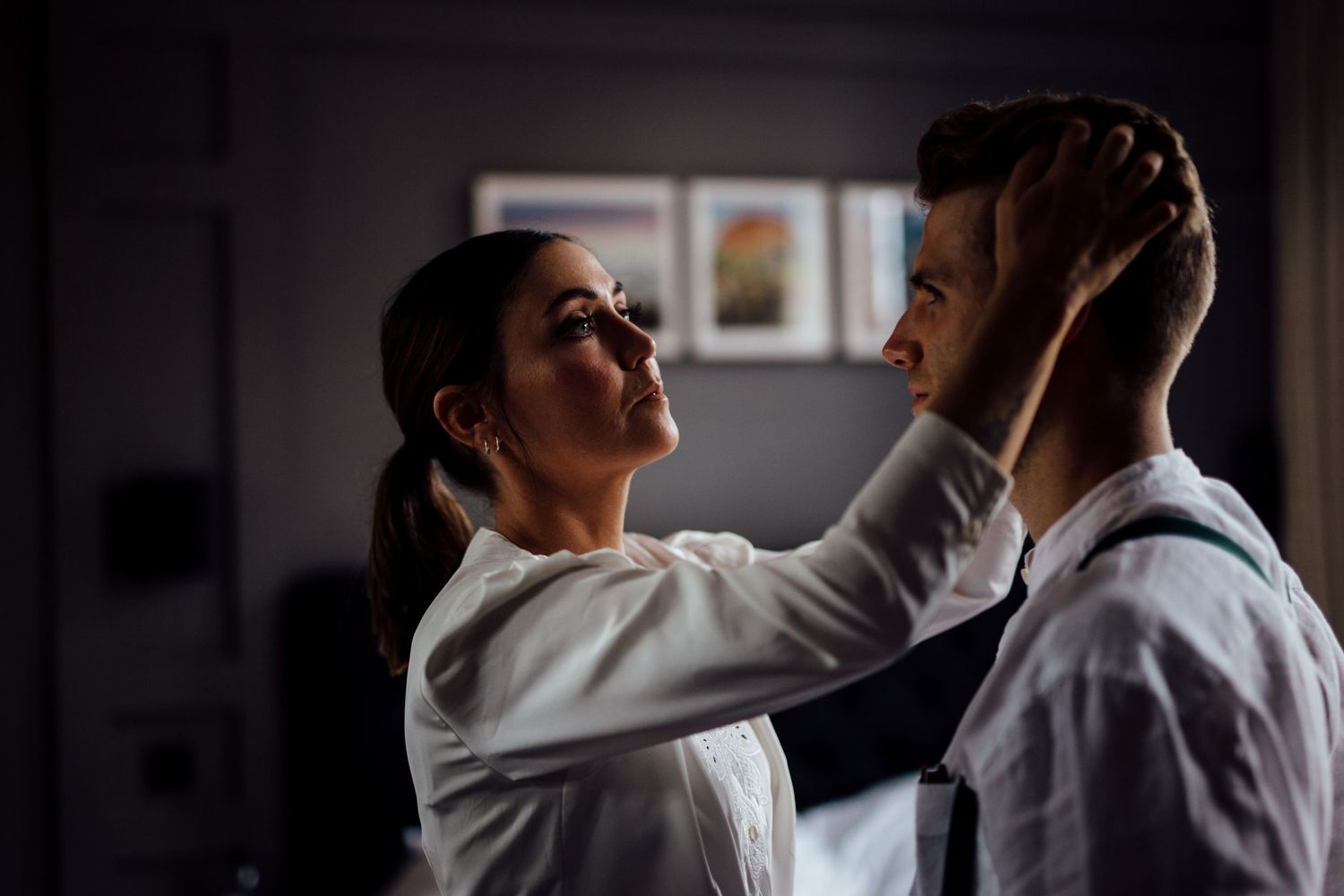 A tender moment between two people in formal attire in a dimly lit room.