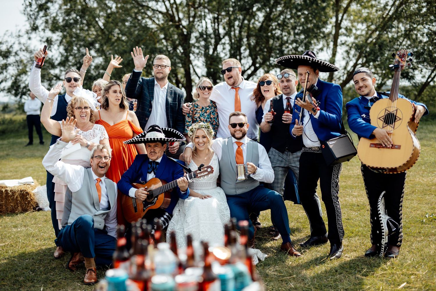 Wedding guests dance and celebrate outdoors on sunny day.