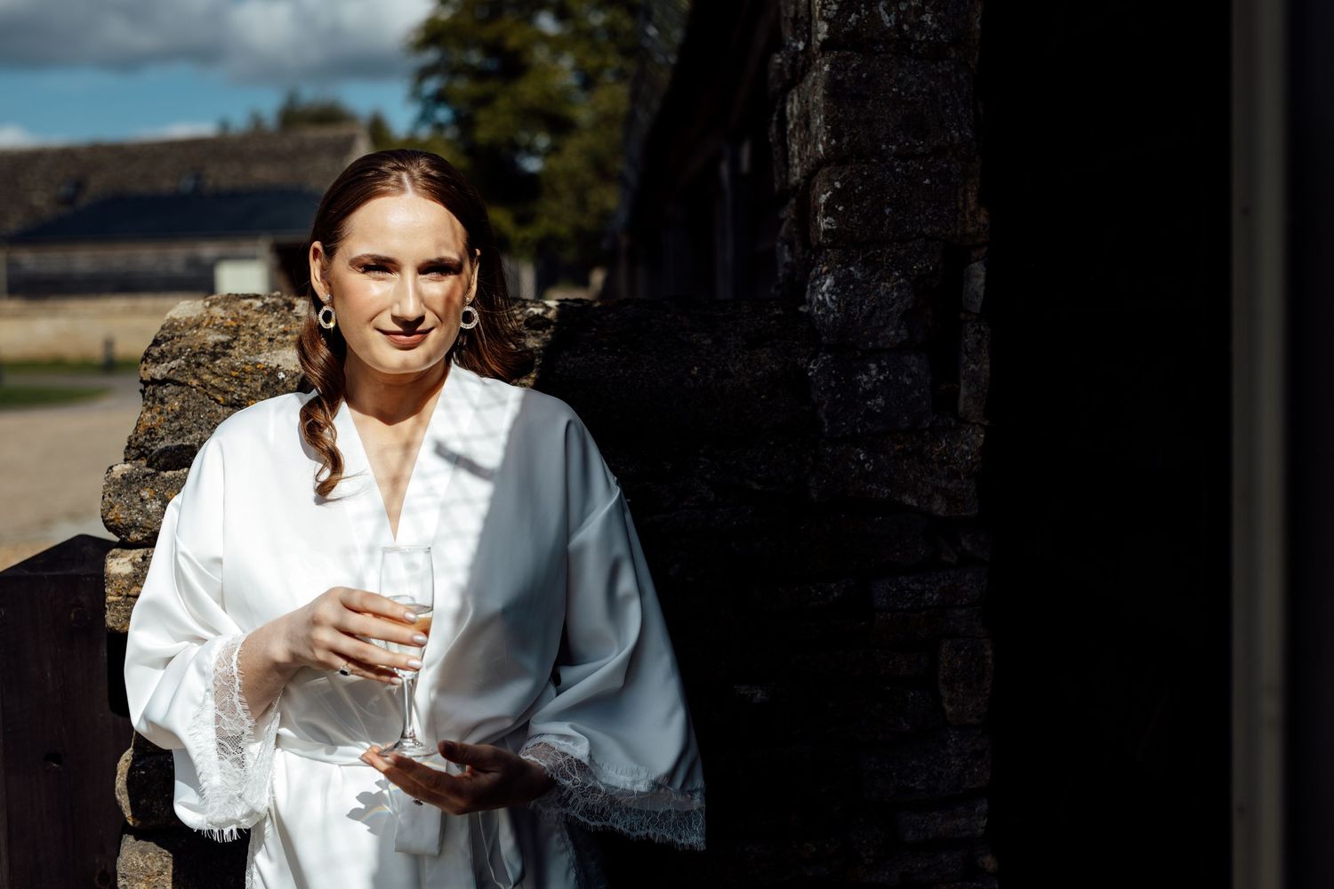 A person in white holds a glass while getting ready before the wedding ceremony.