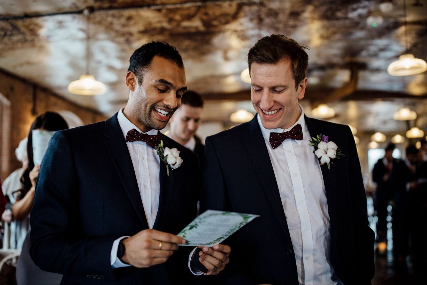 Groomsmen sharing laughs while getting ready in formal black tuxedos.