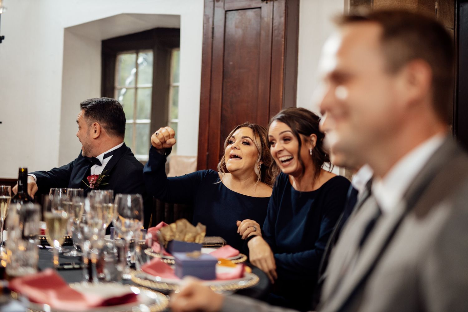 Candid moment of guests laughing during wedding reception dinner.