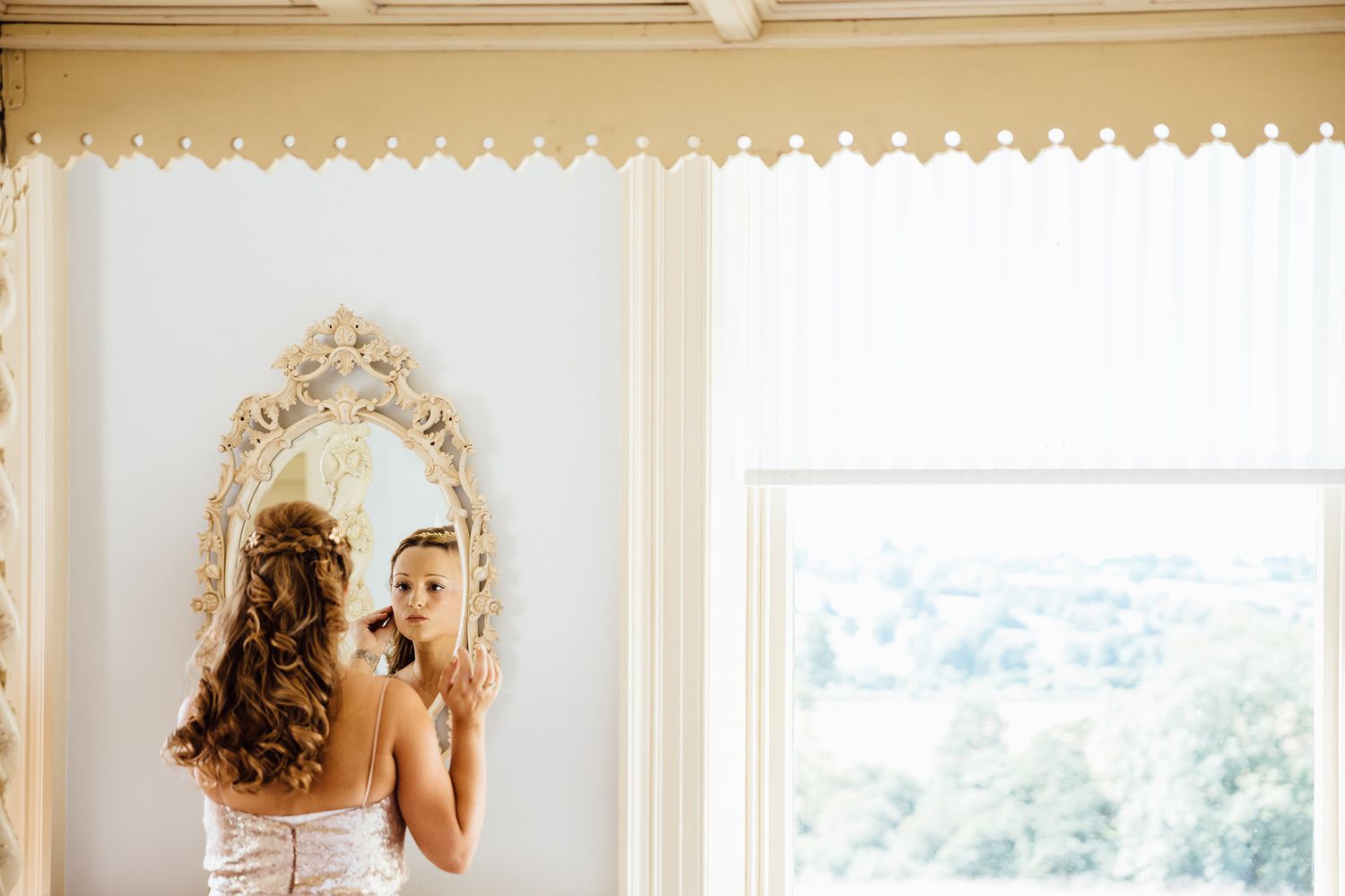 A reflection in an ornate mirror shows a wedding dress detail.