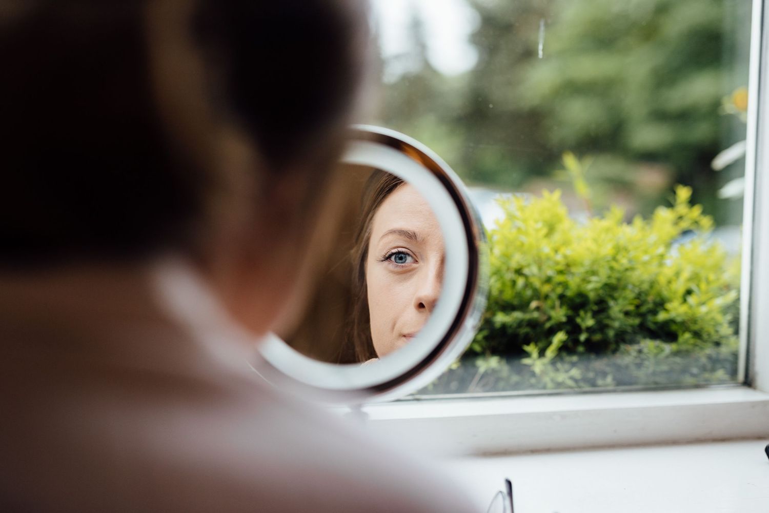 Mirror reflection of wedding day preparations with soft natural window lighting.