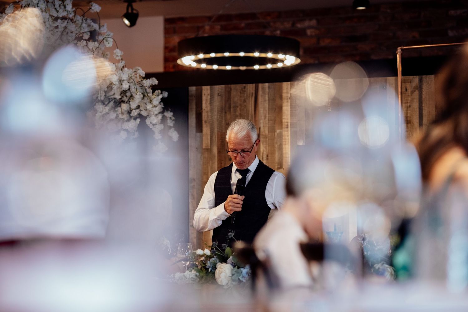 Wedding reception celebration in rustic venue with exposed brick walls and string lights.