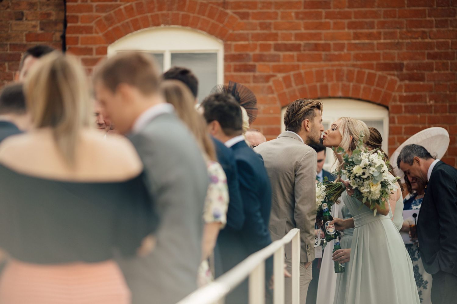 Wedding guests gathering under a brick archway during celebration.