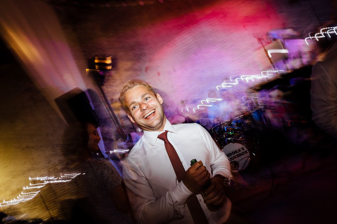 Dance floor lit with vibrant pink and purple lighting during evening wedding reception.