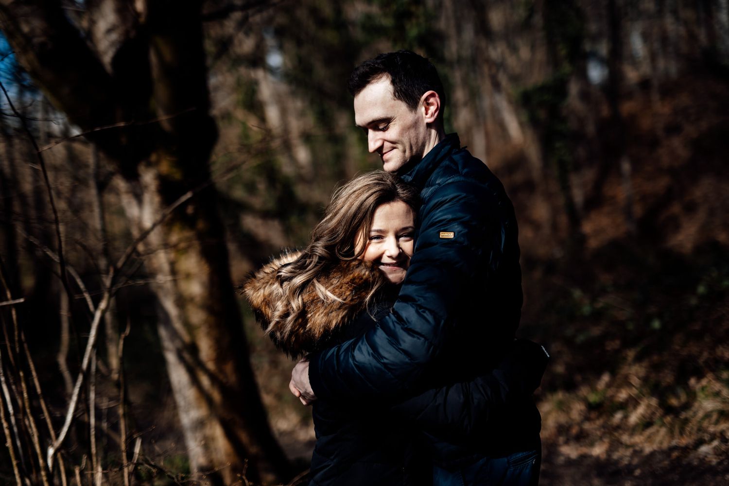 Sunlit forest engagement session with dramatic shadows and light.