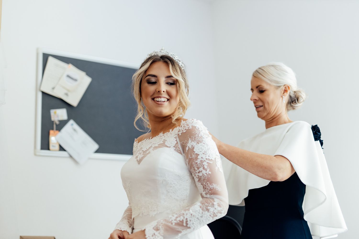 Bridal preparations in a bright white room with elegant decor.