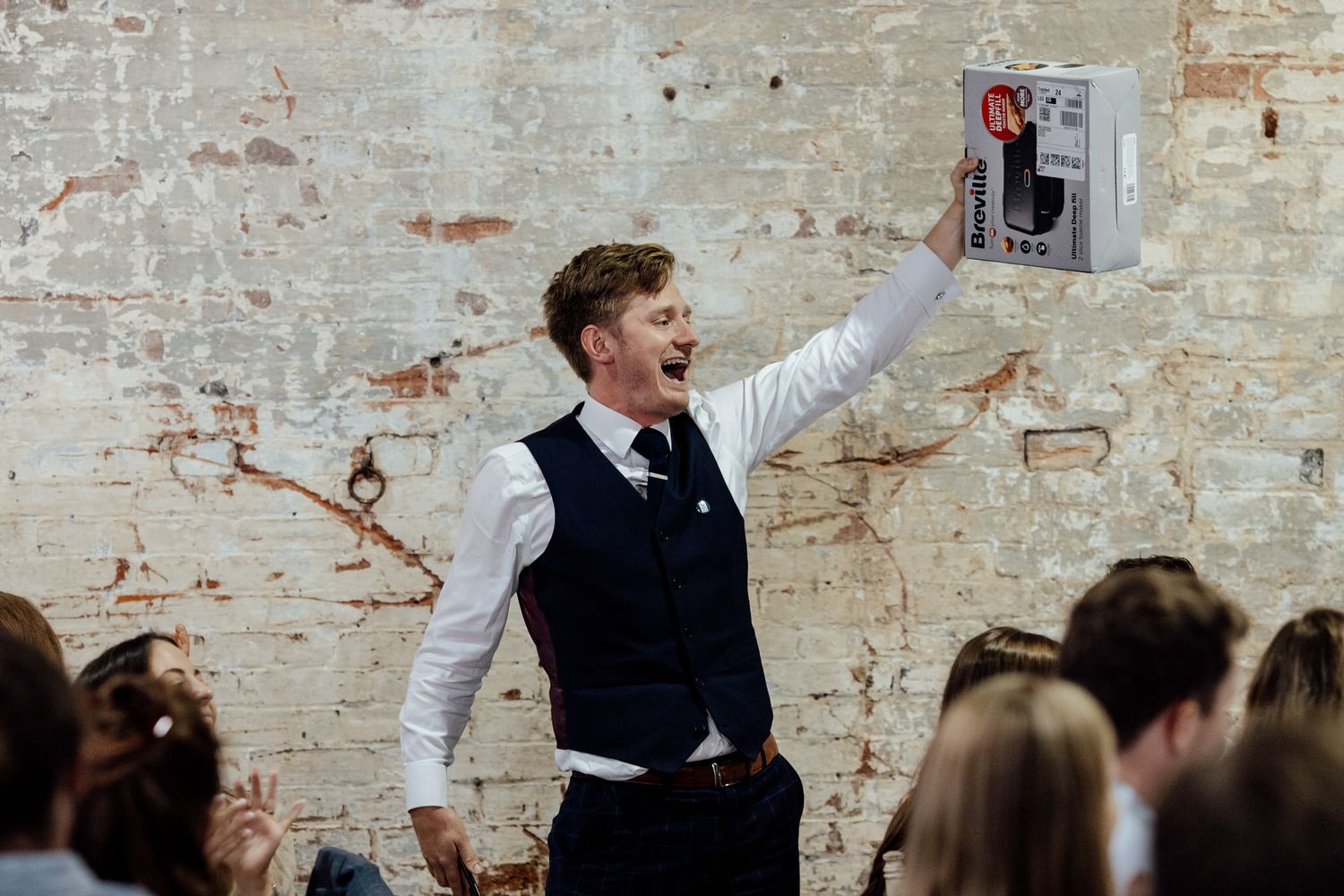 Wedding celebration against weathered brick wall backdrop in rustic venue space.