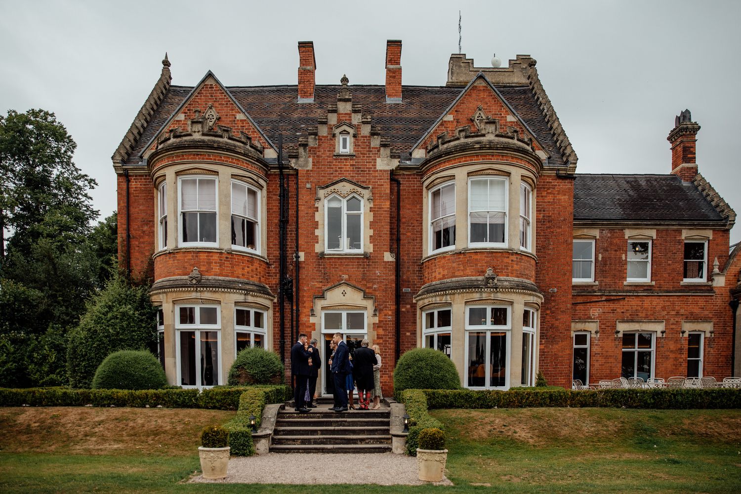 Exterior view of a grand red brick Victorian mansion wedding venue.