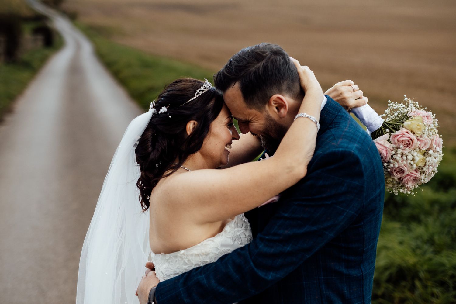 Romantic outdoor wedding photos captured along rural pathway with natural lighting.