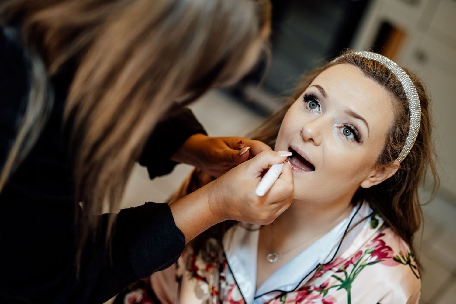 Bride getting her makeup professionally applied during wedding preparations.