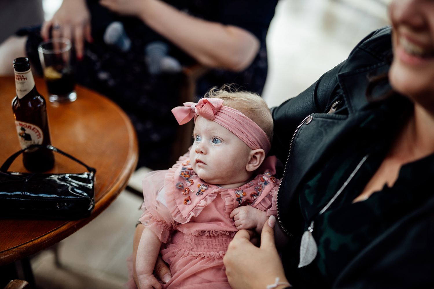 A baby in pink ruffles rests peacefully during wedding festivities.