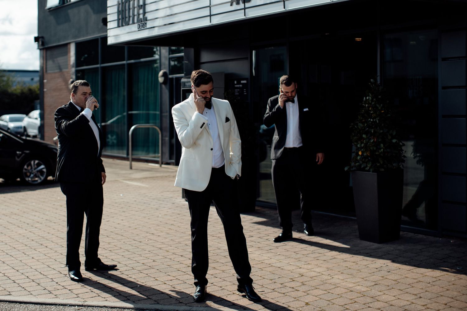 Wedding guests walking on brick pavers outside modern venue building.