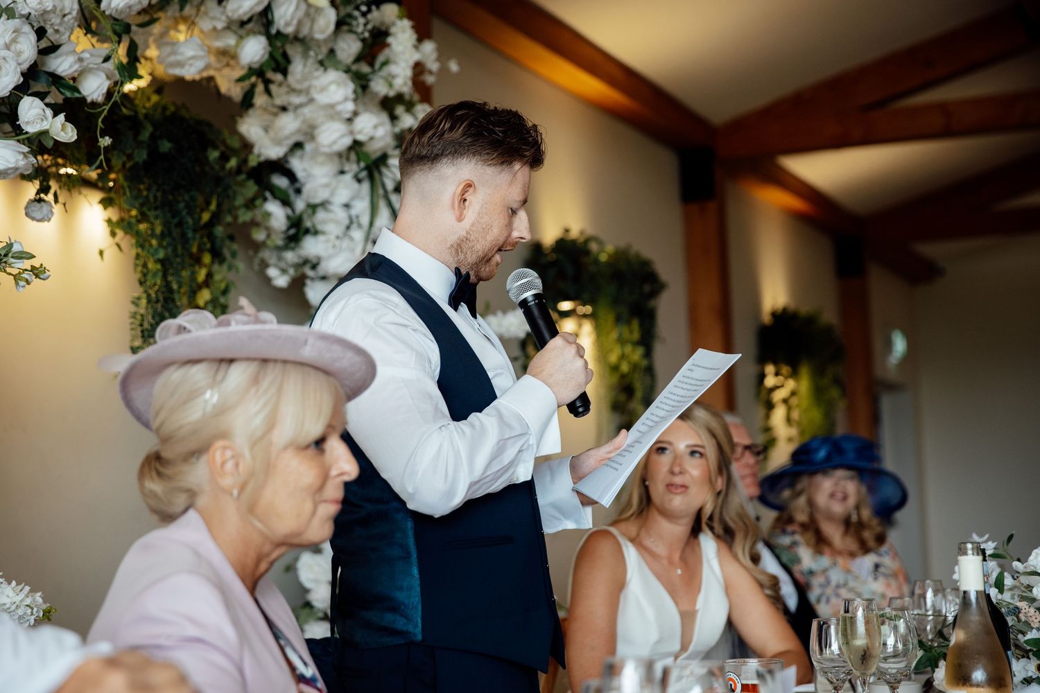Wedding reception dinner setup with elegant floral arrangements and mood lighting.