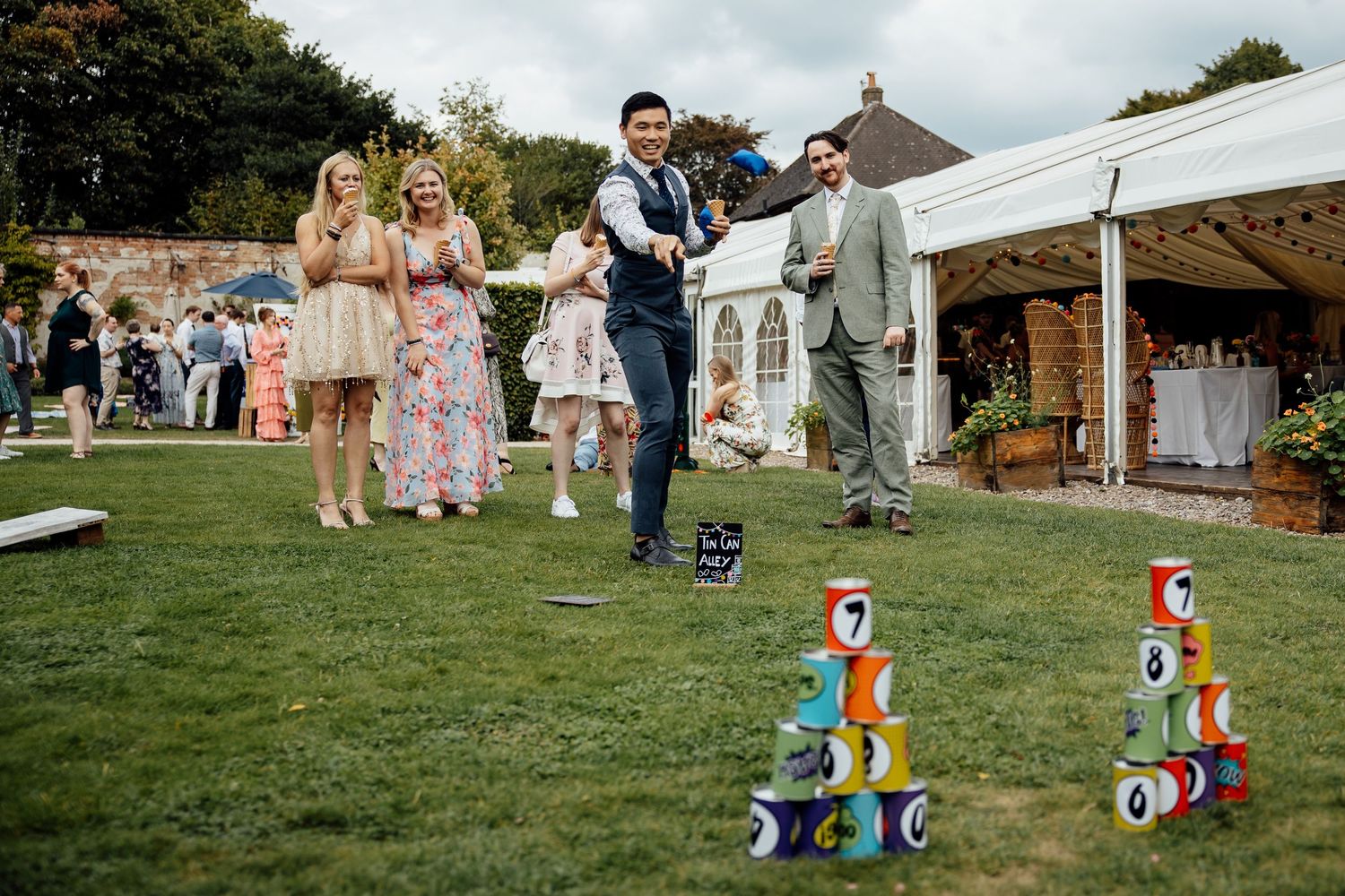 Outdoor wedding lawn games with guests playing with colorful cans stacked as bowling pins.