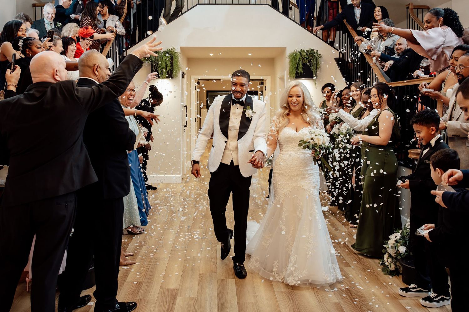 Newlyweds exit through a shower of white confetti as joyful guests celebrate their wedding ceremony.