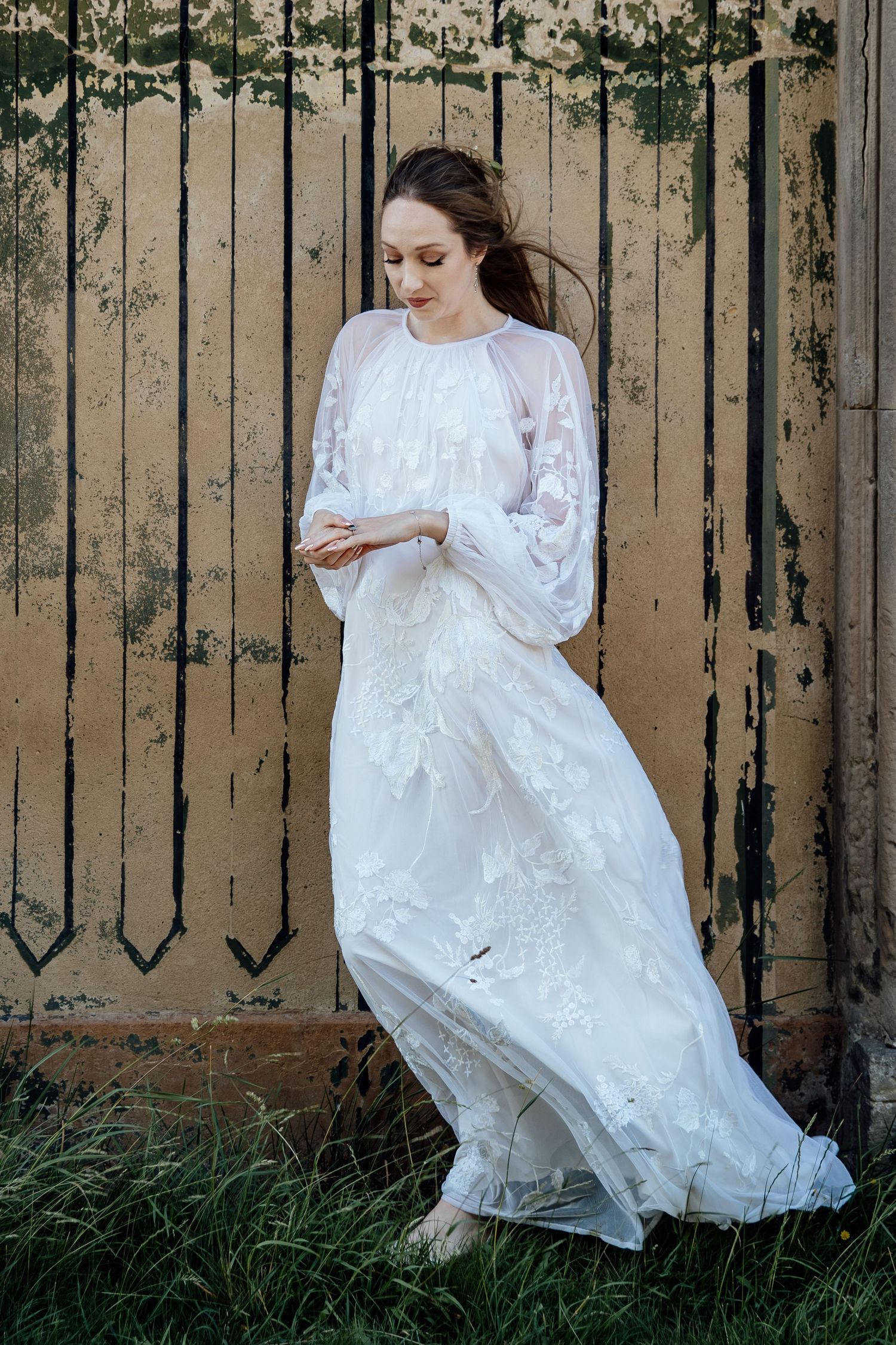 A flowing white vintage dress twirls against a weathered fence backdrop in an artistic photoshoot sequence.