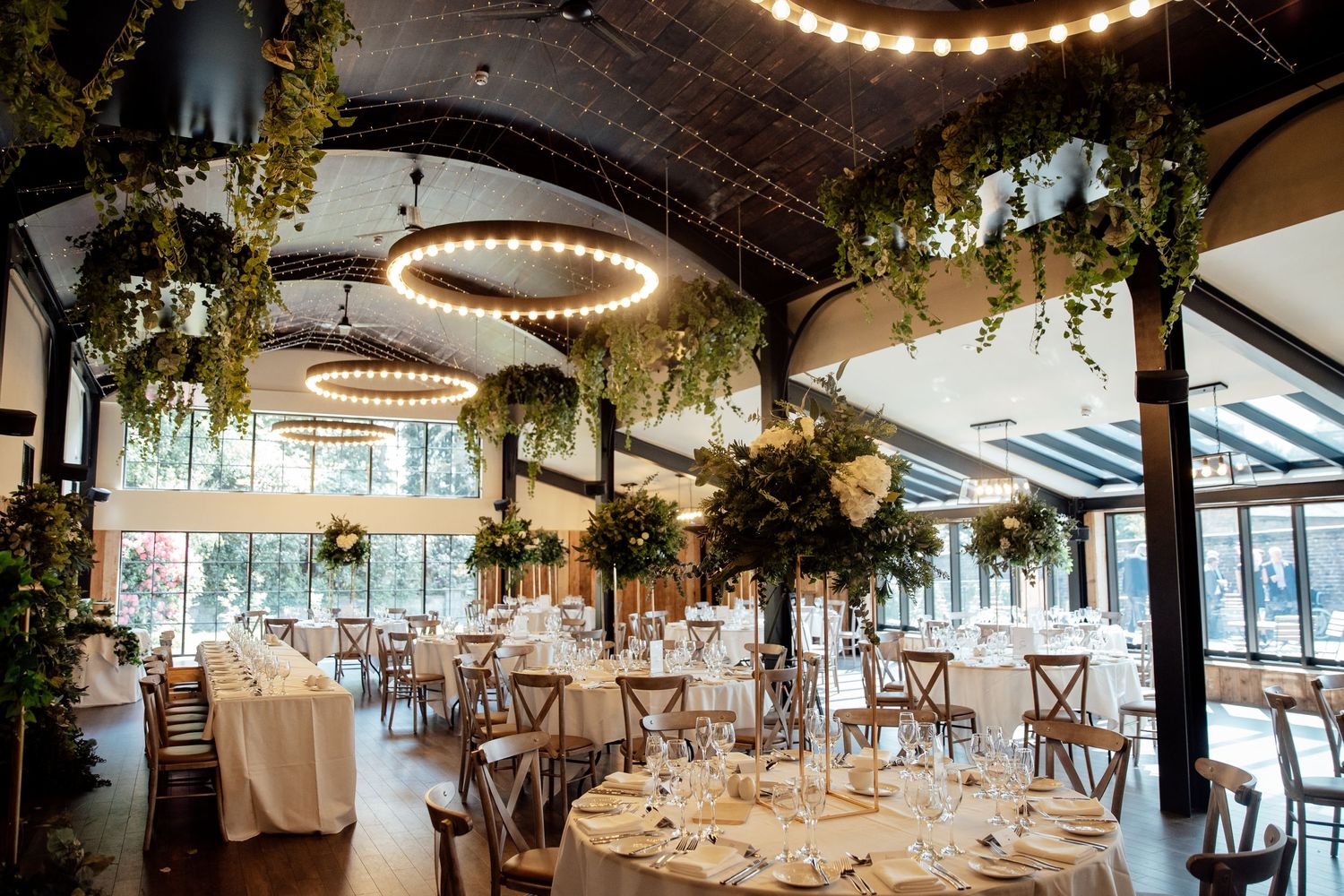 Rustic wedding venue interior decorated with string lights and greenery for reception.