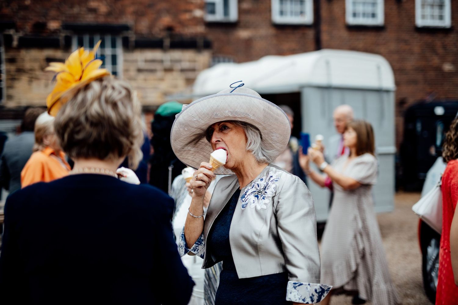 Wedding guests gathered outside a historic brick building during a celebration.