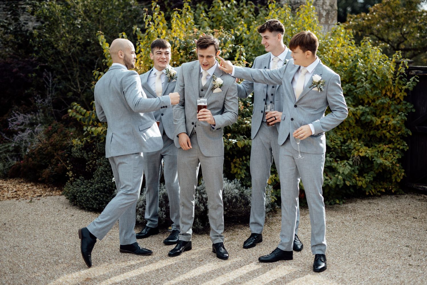 Wedding party in light gray suits posing outdoors.