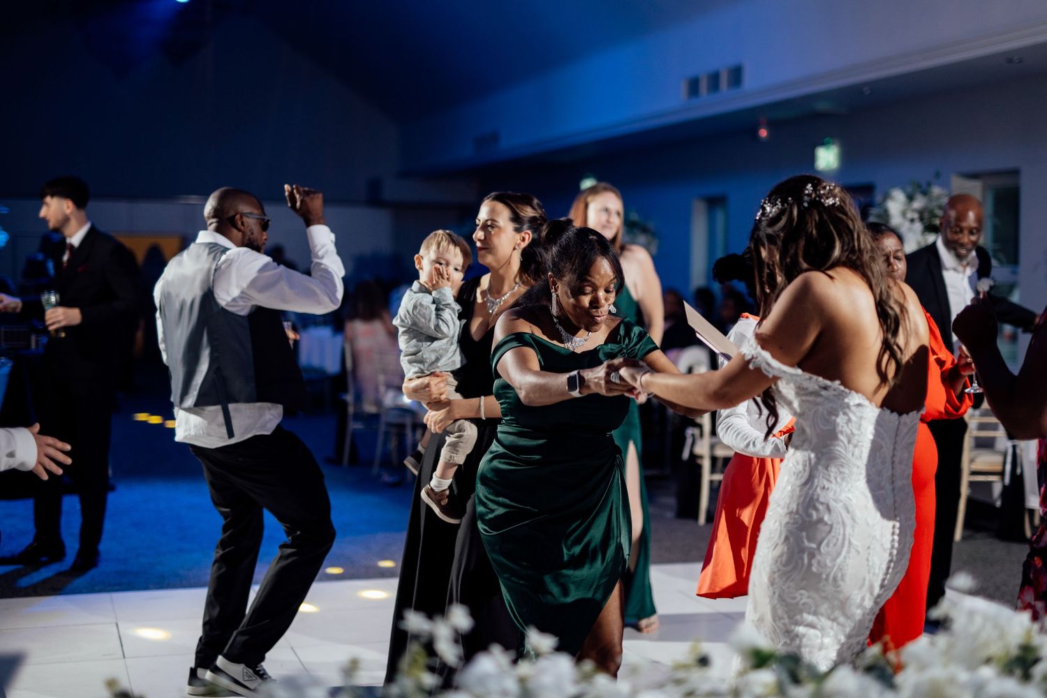 Wedding celebration features energetic dancing and entertainment on a blue-lit dance floor.