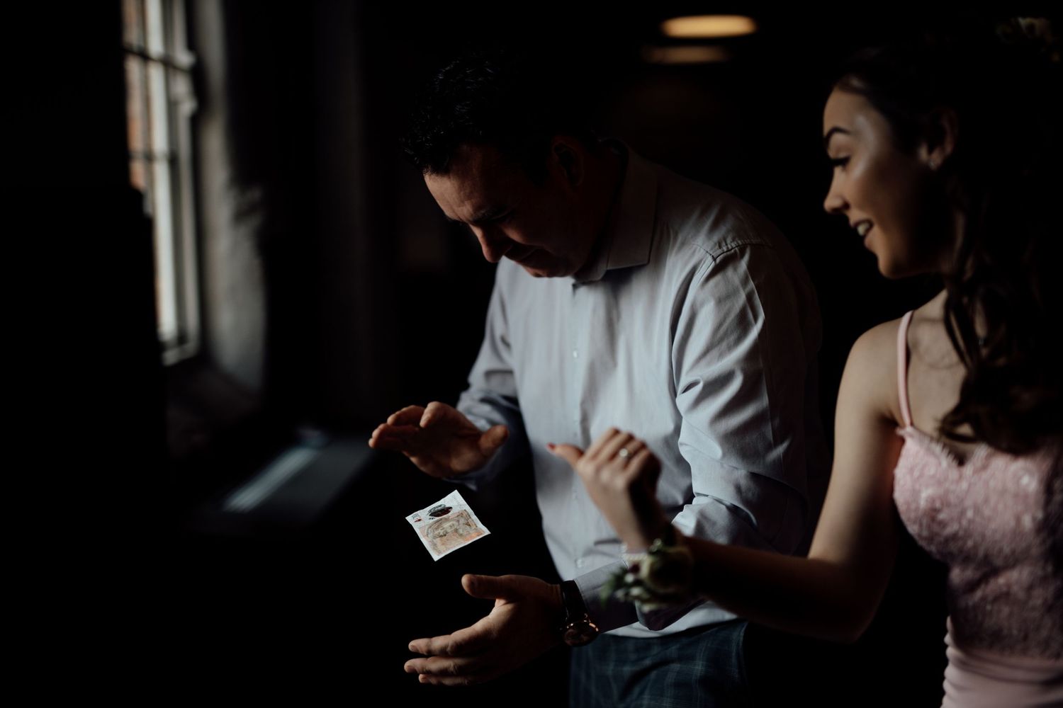 Wedding party enjoying candid moments in a dimly lit venue with brick walls.