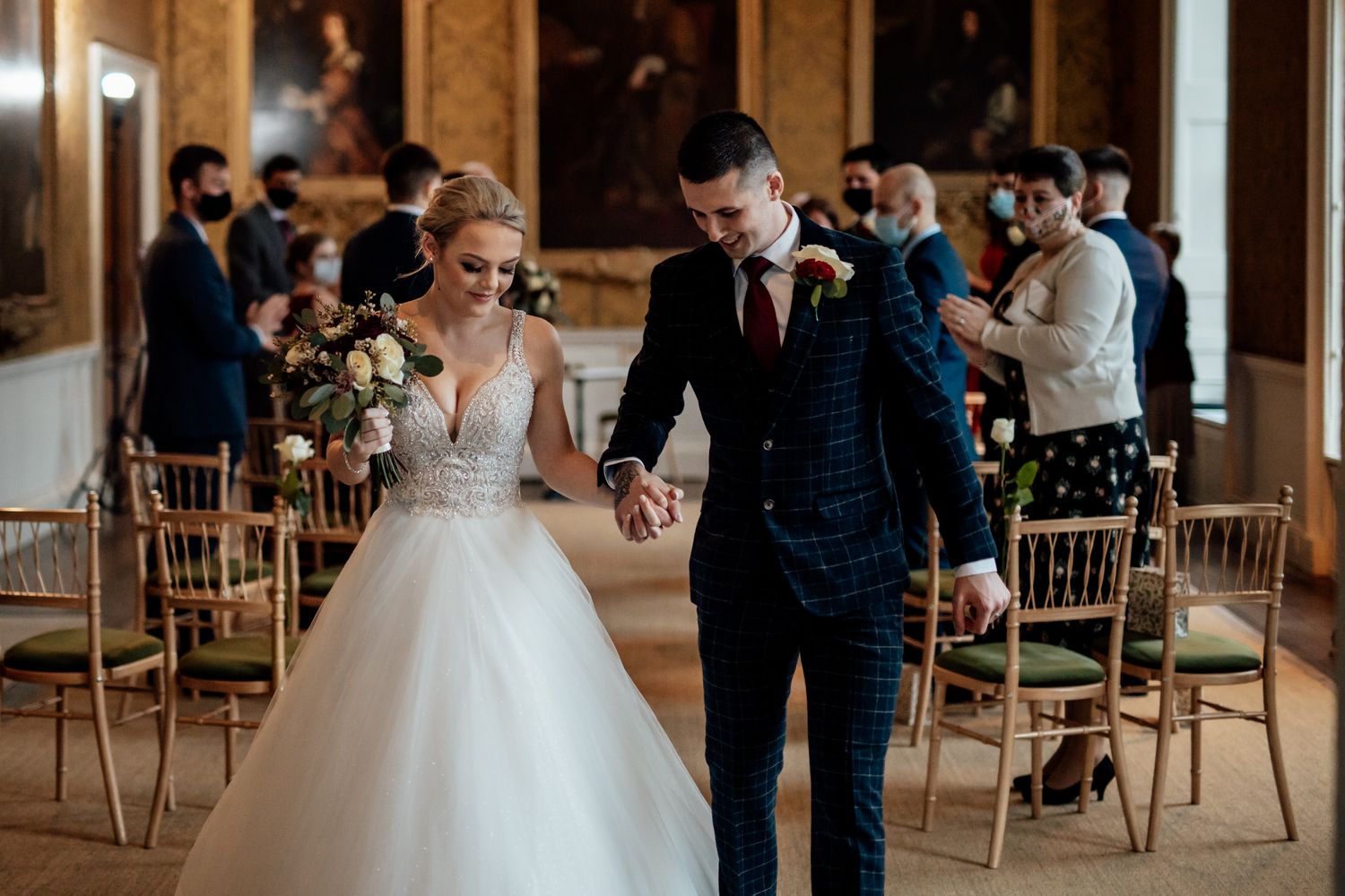 Elegant wedding ceremony setup in a grand room with gold chiavari chairs and natural lighting.