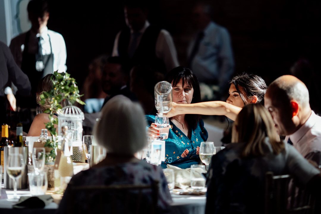 Wedding reception dinner tables illuminated by ambient lighting in a dark atmospheric setting.